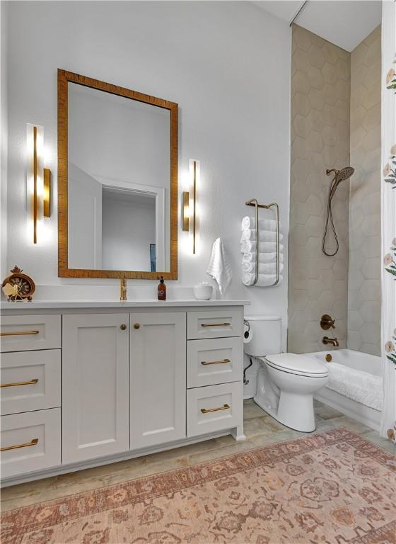 full bathroom with tiled shower / bath combo, vanity, and toilet