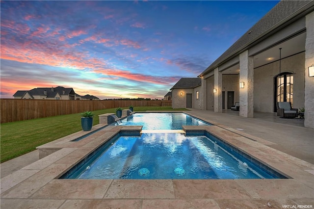 pool at dusk with an in ground hot tub, a patio area, and a lawn