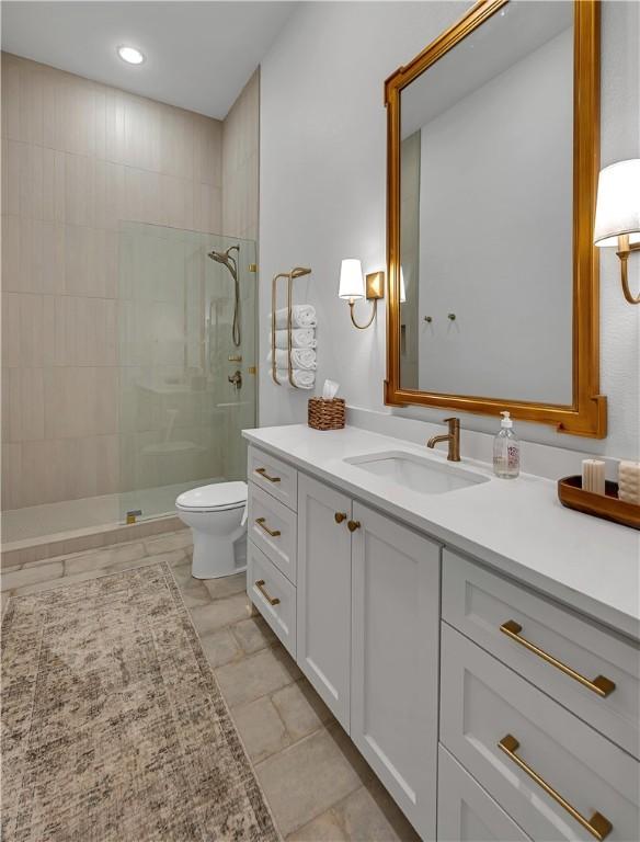 bathroom with tiled shower, vanity, and toilet