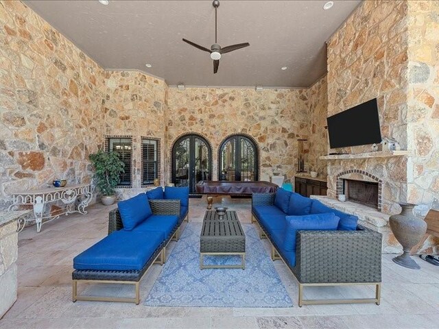 view of patio with an outdoor living space with a fireplace, ceiling fan, and french doors