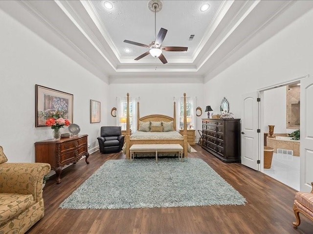 bedroom with connected bathroom, a raised ceiling, ceiling fan, and dark wood-type flooring