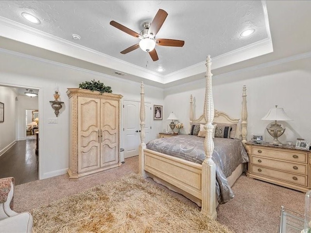 bedroom featuring ceiling fan, light hardwood / wood-style flooring, crown molding, a textured ceiling, and a tray ceiling