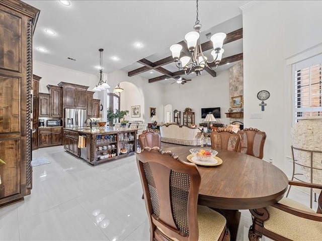 dining room featuring beam ceiling, sink, light tile patterned flooring, and ceiling fan with notable chandelier