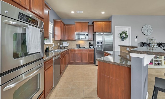 kitchen featuring sink, a breakfast bar area, light tile patterned floors, tasteful backsplash, and stainless steel appliances