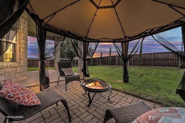 patio terrace at dusk with a gazebo, a yard, and an outdoor fire pit