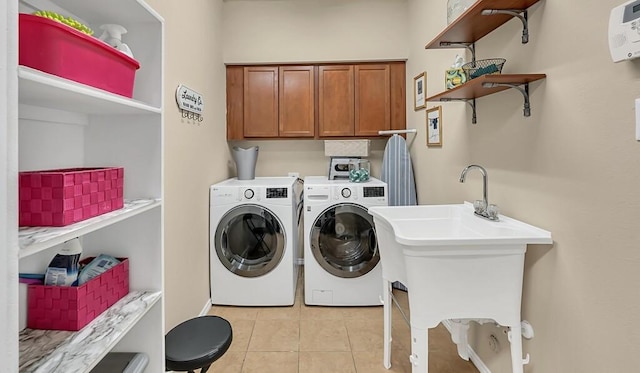 laundry area featuring washer and dryer, sink, cabinets, and light tile patterned flooring