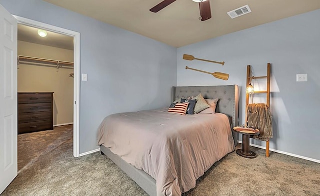 carpeted bedroom featuring a walk in closet, a closet, and ceiling fan