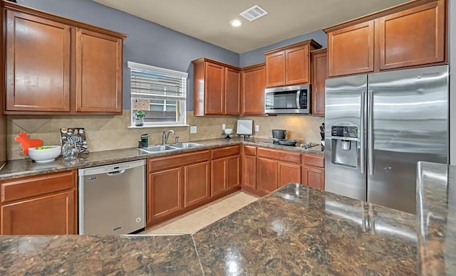 kitchen with sink, stainless steel appliances, dark stone counters, and tasteful backsplash