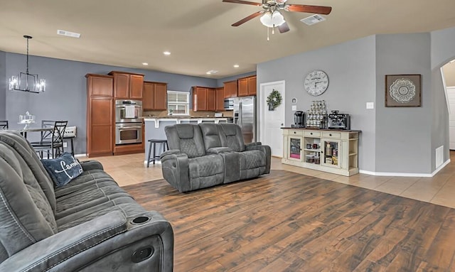 living room featuring light wood-type flooring and ceiling fan with notable chandelier