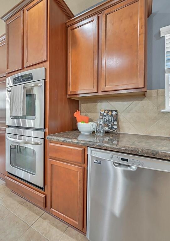 kitchen featuring decorative backsplash, light tile patterned flooring, and appliances with stainless steel finishes