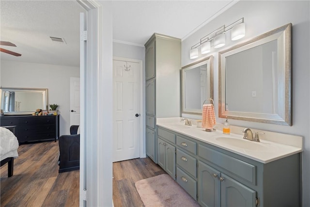 bathroom with ceiling fan, vanity, wood-type flooring, and ornamental molding