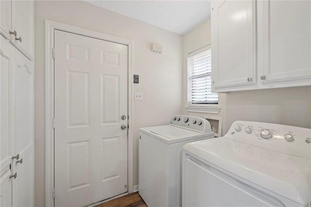 laundry room with washing machine and clothes dryer, dark wood-type flooring, and cabinets