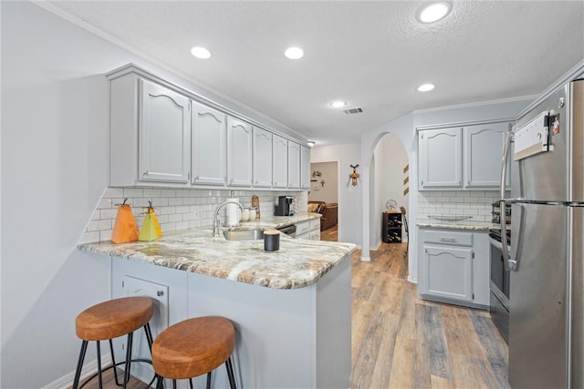 kitchen with kitchen peninsula, light wood-type flooring, a breakfast bar, and stainless steel appliances