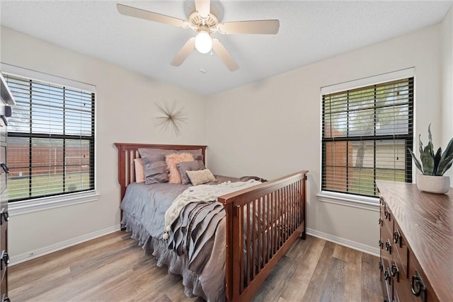 bedroom with multiple windows, ceiling fan, and wood-type flooring