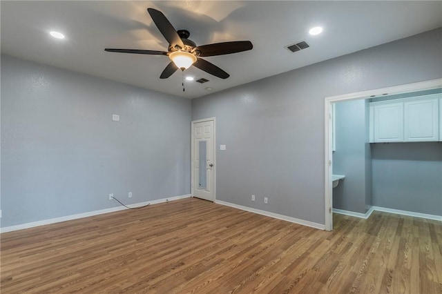 empty room with ceiling fan and light hardwood / wood-style flooring