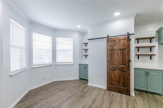 interior space featuring crown molding, light hardwood / wood-style floors, and a barn door