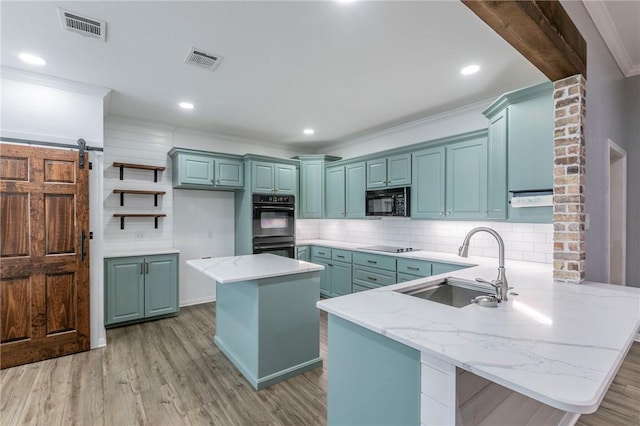 kitchen featuring sink, kitchen peninsula, a kitchen island, a barn door, and decorative backsplash