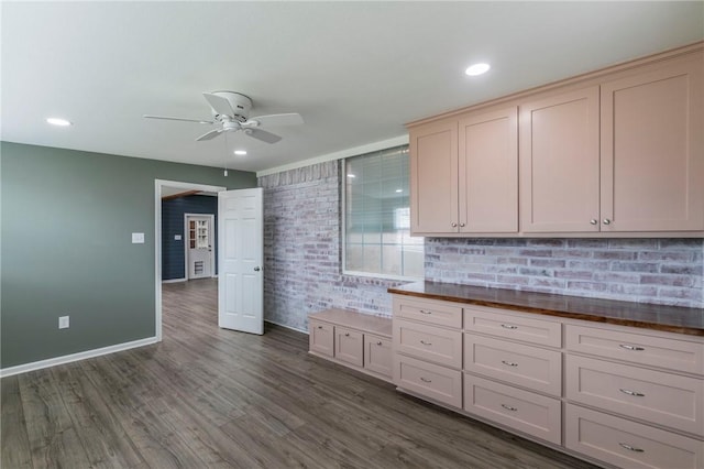 kitchen featuring ceiling fan, brick wall, dark hardwood / wood-style flooring, and butcher block counters