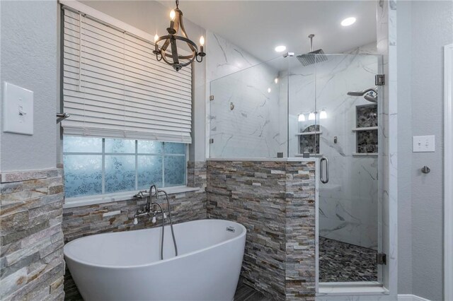 bathroom with a notable chandelier and independent shower and bath