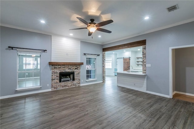 unfurnished living room featuring dark wood-type flooring, ceiling fan, and a barn door