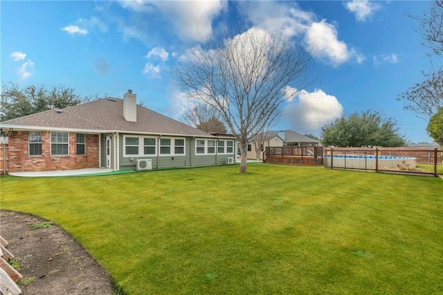 rear view of house featuring a patio, a fenced in pool, a lawn, and ac unit