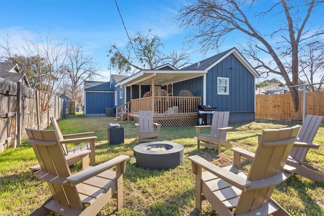 back of house with a lawn, an outdoor fire pit, and a wooden deck