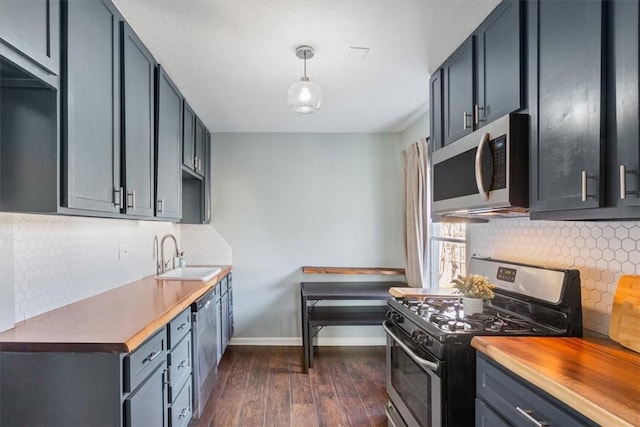 kitchen featuring hanging light fixtures, dark hardwood / wood-style flooring, sink, appliances with stainless steel finishes, and butcher block counters