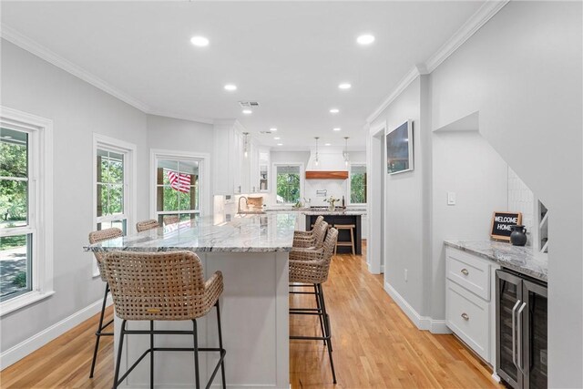 kitchen with white cabinets, a kitchen breakfast bar, light hardwood / wood-style flooring, and ornamental molding