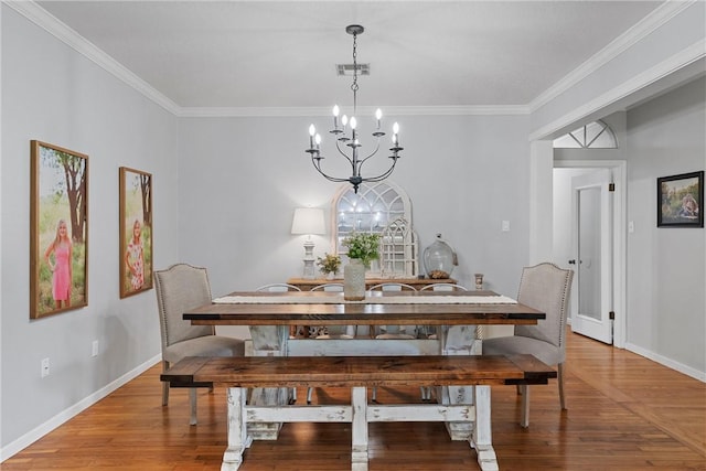 dining space with hardwood / wood-style floors, crown molding, and a chandelier