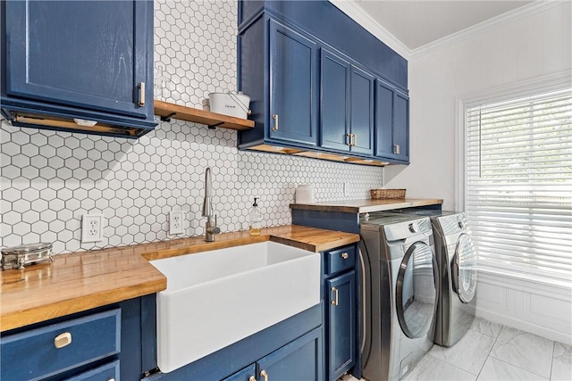 clothes washing area with washer and dryer, cabinets, ornamental molding, and sink