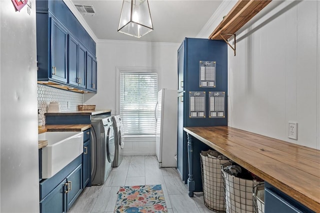 laundry area featuring separate washer and dryer, sink, cabinets, and ornamental molding