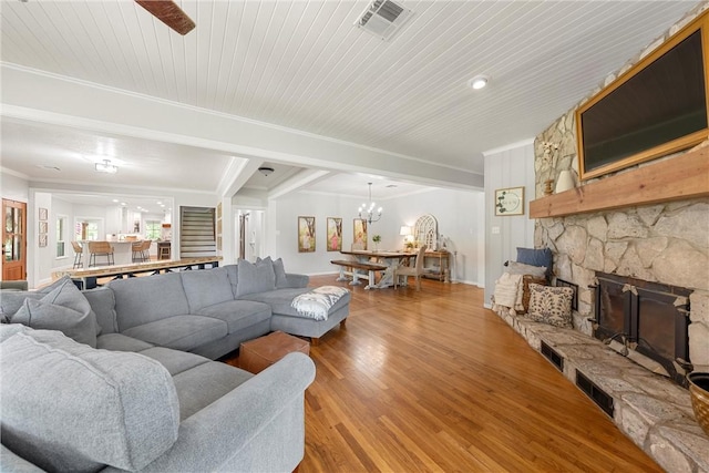 living room with wooden ceiling, crown molding, a fireplace, ceiling fan with notable chandelier, and light wood-type flooring