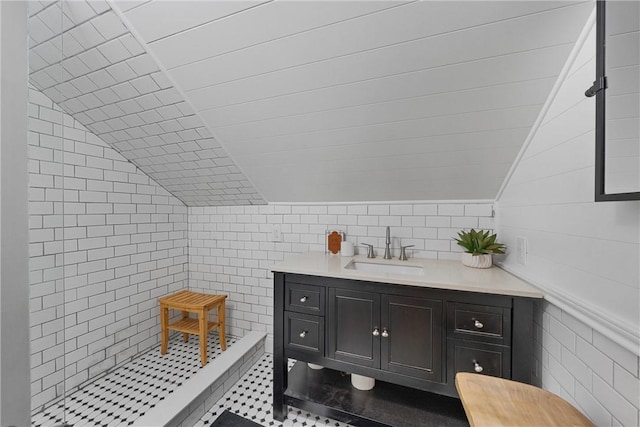 bathroom with vanity, a shower, lofted ceiling, and tile walls