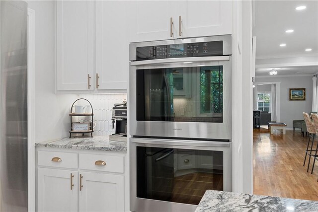 kitchen featuring decorative backsplash, white cabinetry, light hardwood / wood-style flooring, and appliances with stainless steel finishes