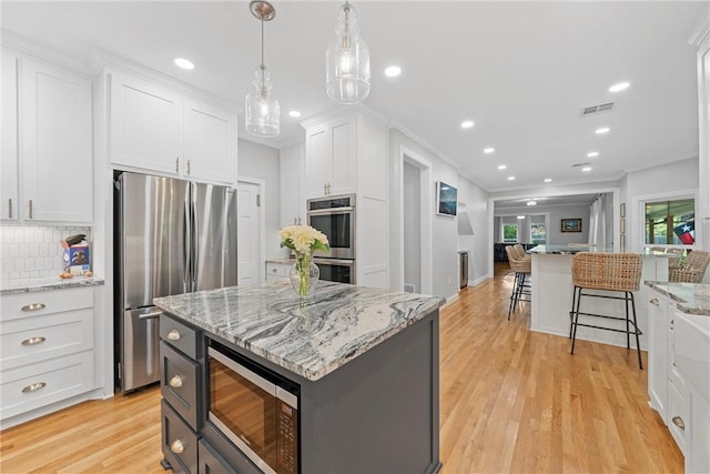 kitchen with white cabinets, appliances with stainless steel finishes, light wood-type flooring, and a kitchen island