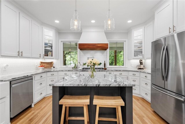 kitchen with premium range hood, tasteful backsplash, white cabinets, and stainless steel appliances