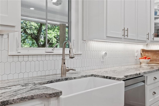 kitchen featuring backsplash, light stone countertops, sink, and white cabinets