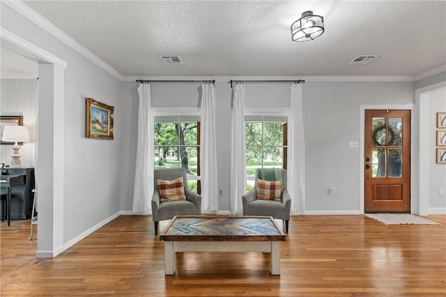 living area featuring ornamental molding, a textured ceiling, and light hardwood / wood-style flooring