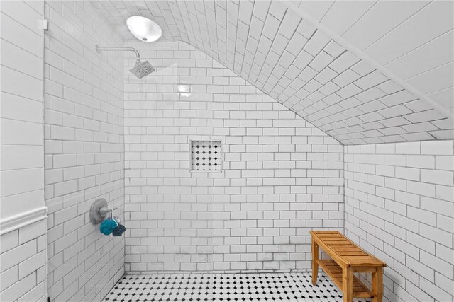 bathroom featuring a tile shower and lofted ceiling