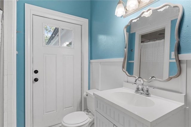 bathroom with curtained shower, vanity, and toilet