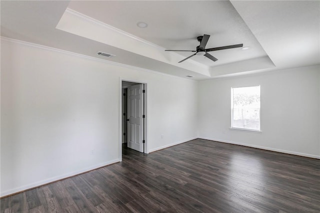 spare room featuring a raised ceiling, ceiling fan, dark wood-type flooring, and crown molding