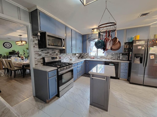 kitchen featuring appliances with stainless steel finishes, blue cabinets, hanging light fixtures, a kitchen island, and sink