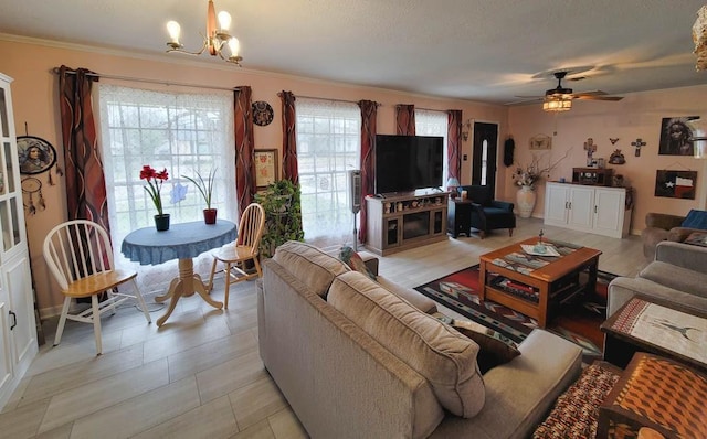 living room featuring ceiling fan with notable chandelier, ornamental molding, and a textured ceiling