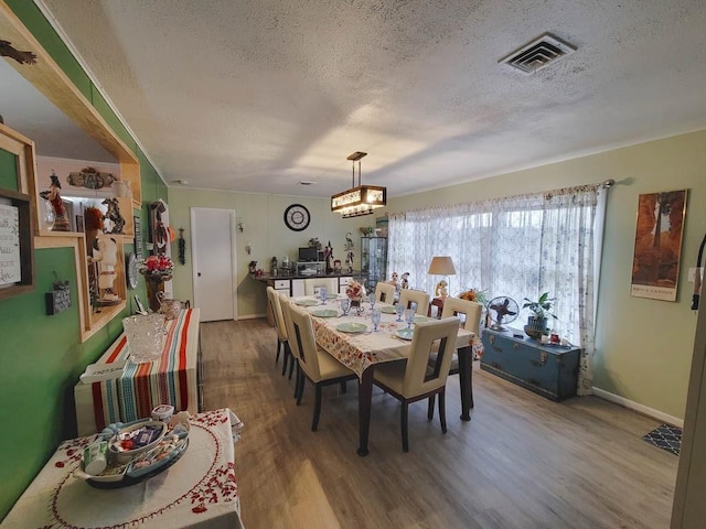 dining space with hardwood / wood-style floors, a textured ceiling, and an inviting chandelier