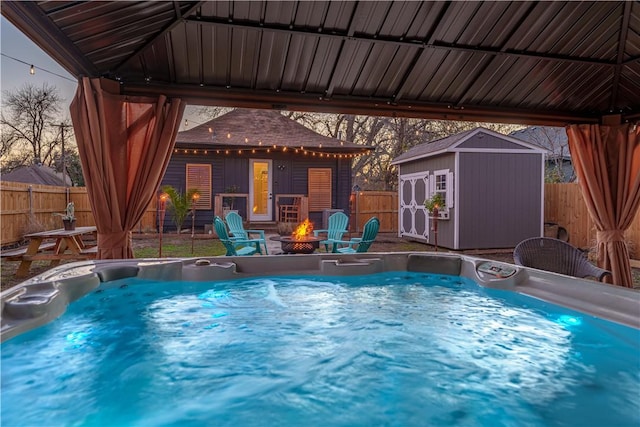 view of swimming pool with an outdoor structure, a fenced backyard, and a hot tub