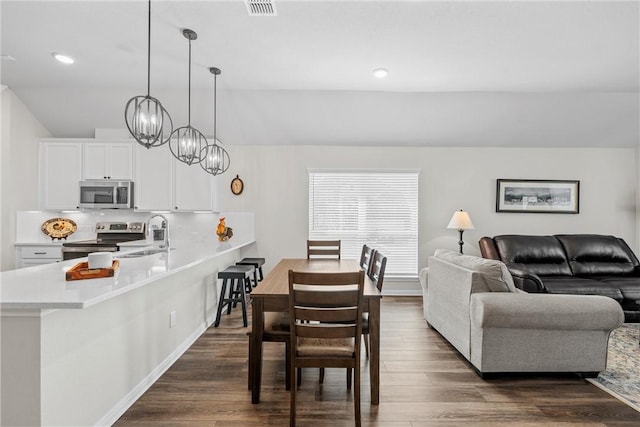 dining room featuring vaulted ceiling, sink, dark hardwood / wood-style floors, and an inviting chandelier