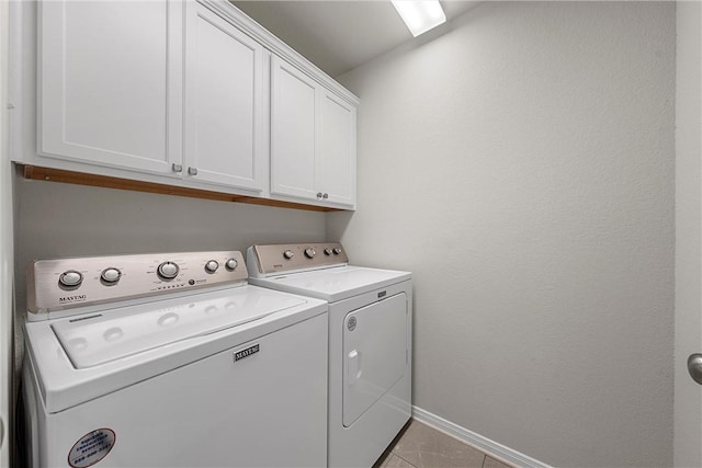 clothes washing area with light tile patterned flooring, cabinets, and separate washer and dryer