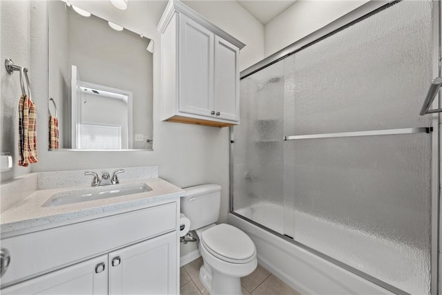 full bathroom with tile patterned floors, vanity, bath / shower combo with glass door, and toilet