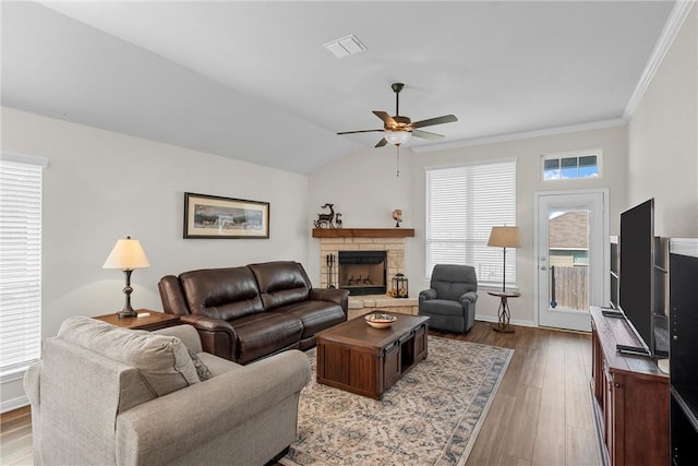 living room with a wealth of natural light, crown molding, wood-type flooring, and lofted ceiling