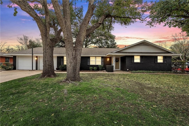 single story home featuring a garage, driveway, and a yard